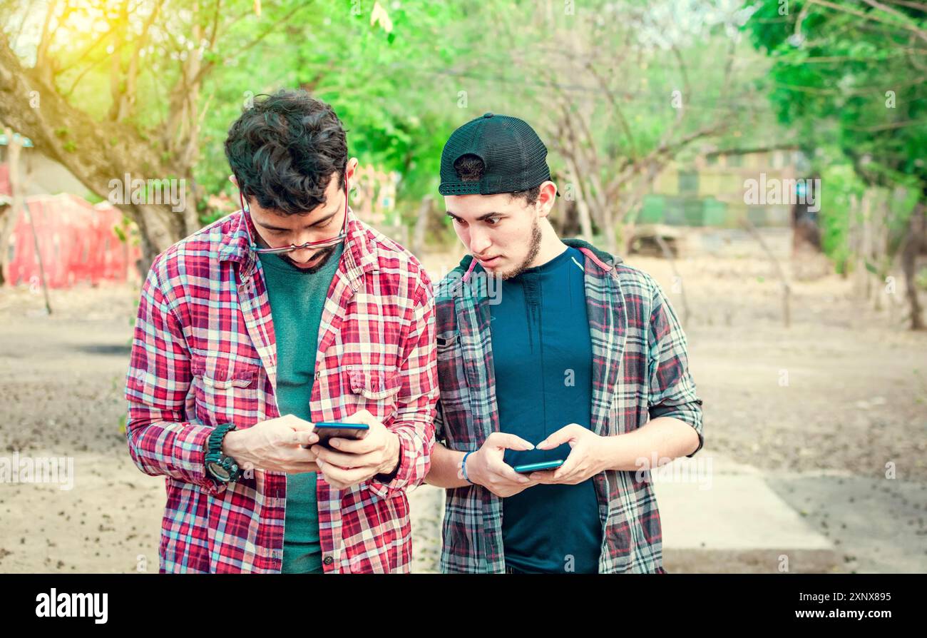 Un ami jaloux qui espionne le téléphone portable de son ami à l'extérieur, un ami qui espionne le téléphone de son ami. Un gars snooping sur le téléphone de son ami dans la rue Banque D'Images