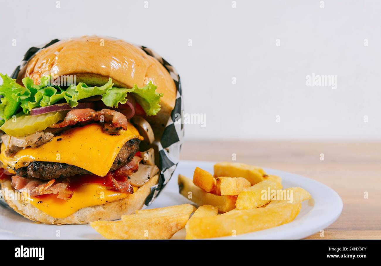 Hamburger fait maison avec des frites sur une assiette sur une table en bois. Grand cheeseburger avec frites servi avec espace de copie Banque D'Images