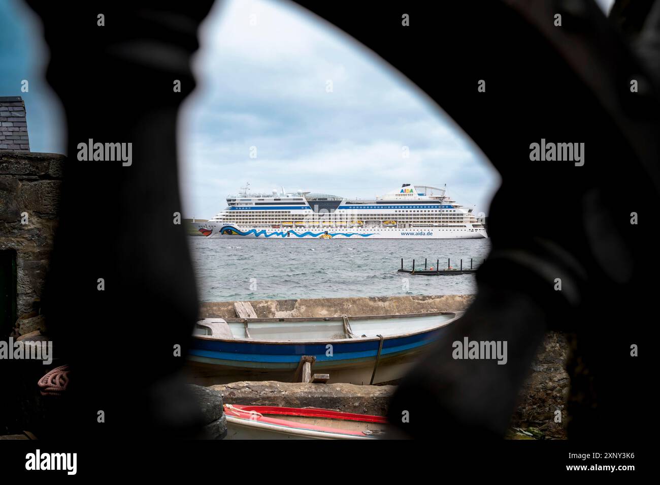 Vue du bateau de croisière aida Bella à travers la roue en bois ancrée en Écosse avec un petit bateau devant Banque D'Images