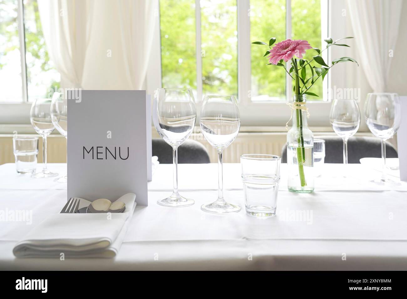 Décor de table élégant, place avec carte de menu, verres, couverts, serviette et une fleur rose sur une nappe blanche pour une célébration festive du dîner, copie Banque D'Images