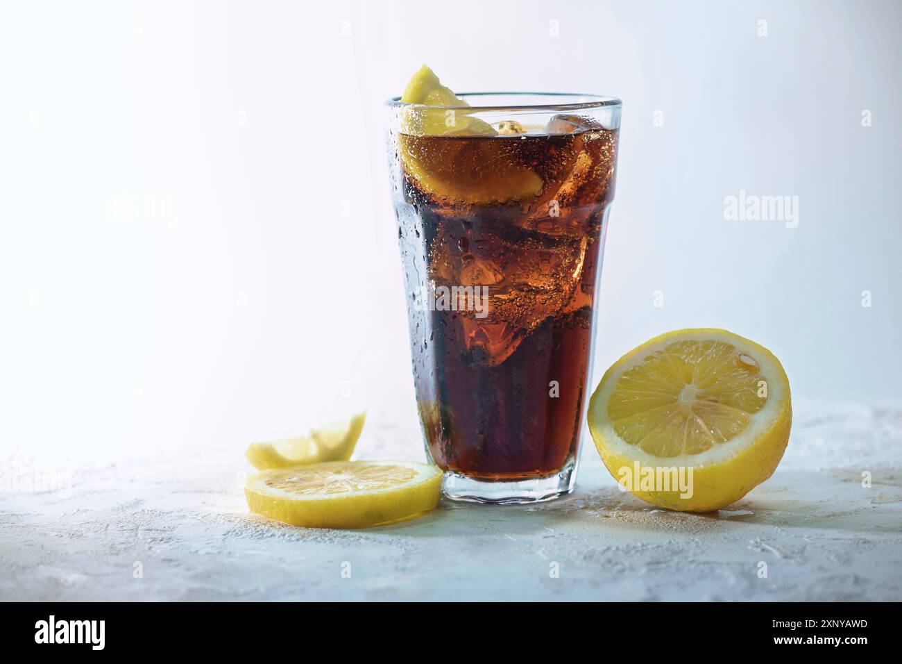 Cola frais avec des glaçons et des tranches de citron dans un verre à boire sur un fond gris bleu clair, boisson rafraîchissante de caféine sucrée, espace de copie Banque D'Images