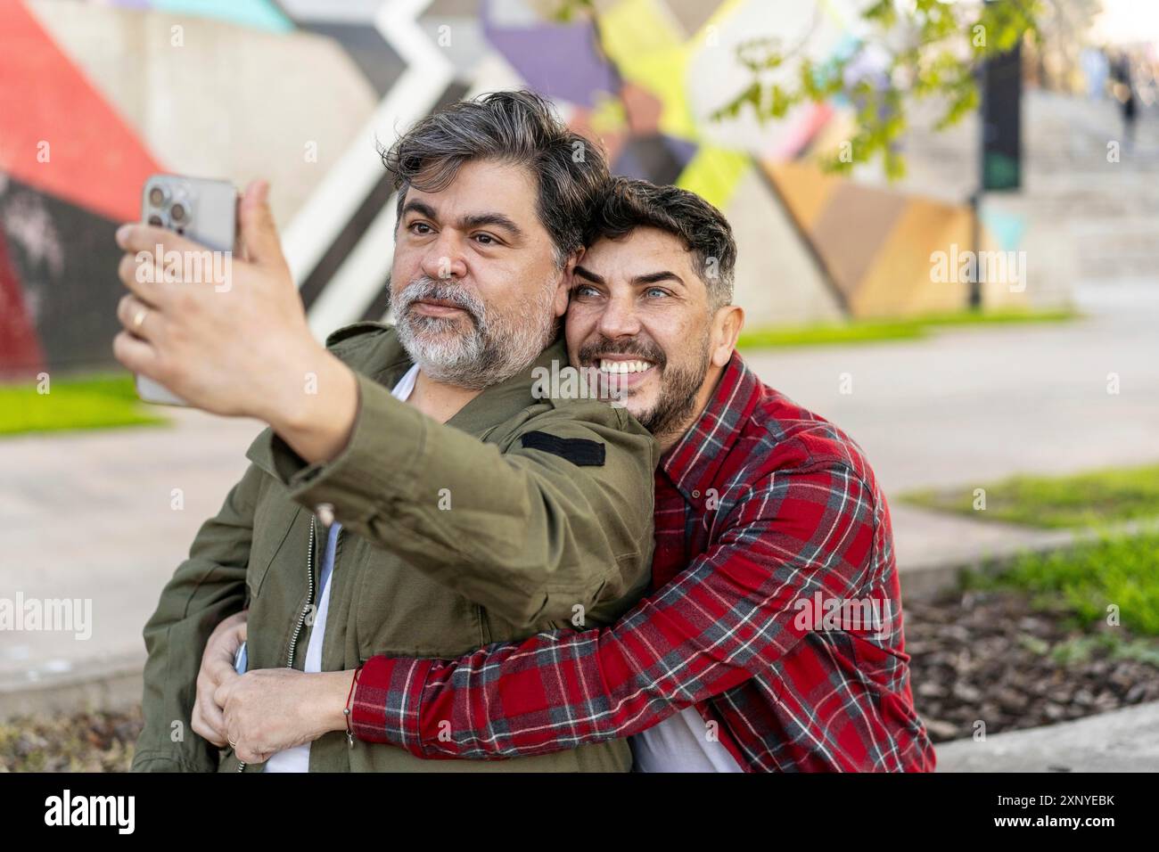 Heureux couple gay prenant une pause dans la rue et prenant un selfie Banque D'Images