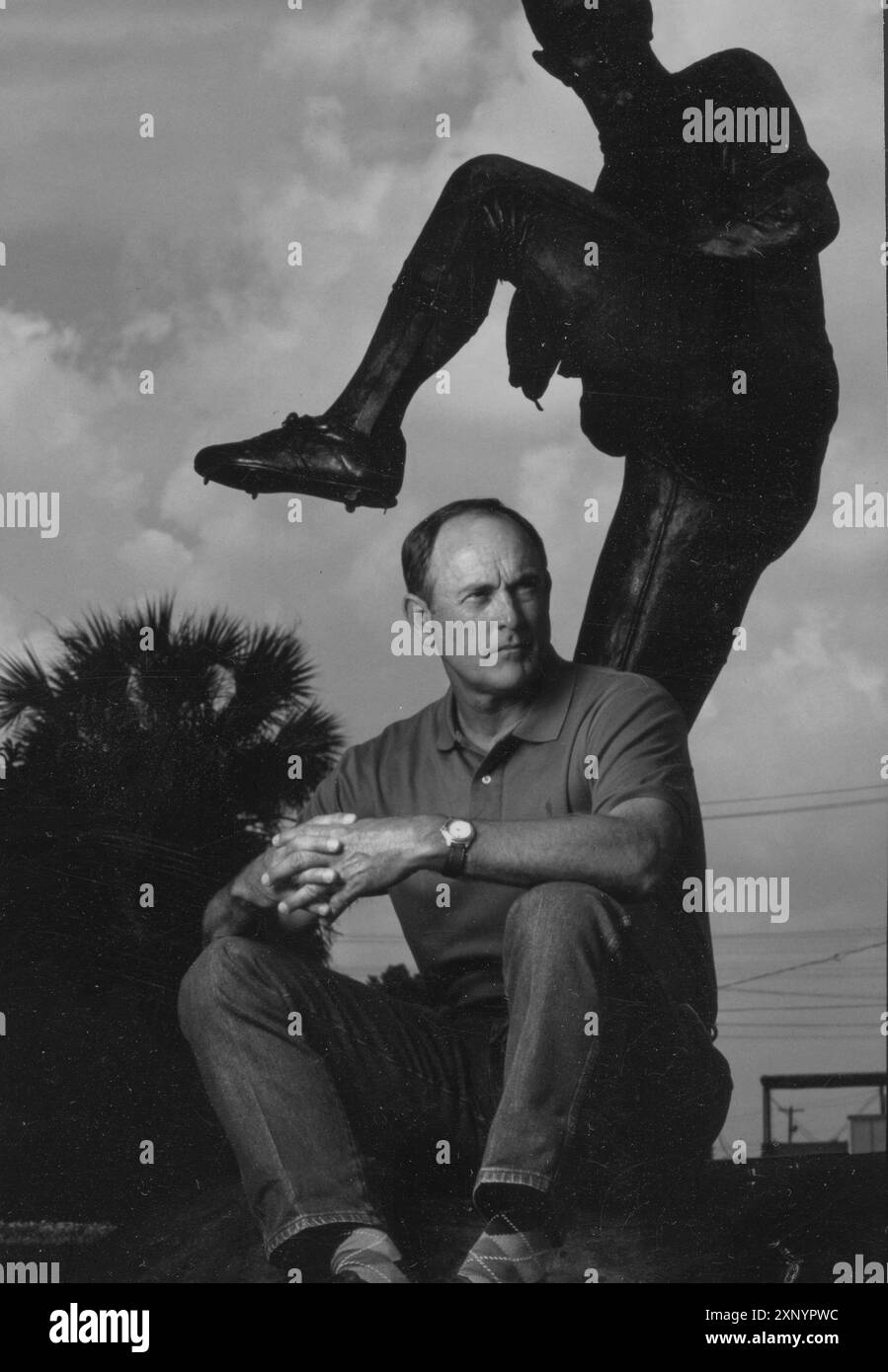 Le lanceur du Hall of Fame du baseball NOLAN RYAN pose dans le centre-ville d'Alvin, Texas, à côté d'une statue de lui-même en train de lancer. La statue en bronze a été réalisée par le sculpteur Jack Bryant et dévoilée en 1992 devant l'hôtel de ville d'Alvin. Ceci a été photographié pour le programme All-Star 1995. Original en couleur ©Bob Daemmrich Banque D'Images