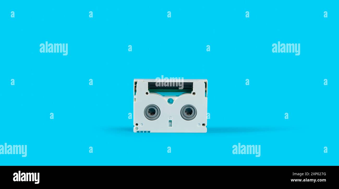 Vue avant de la vieille mini cassette DV blanche sur une surface bleue sur fond bleu Banque D'Images
