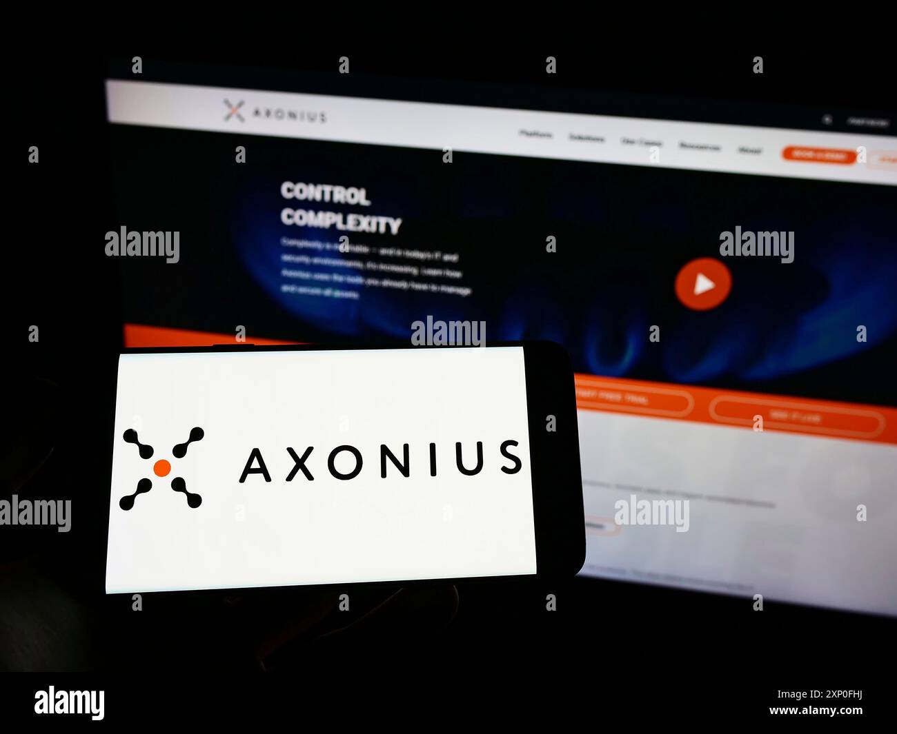 Stuttgart, Allemagne, 03-12-2022 : personne tenant un téléphone portable avec le logo de la société américaine de cybersécurité Axonius Inc sur l'écran devant la page web. Banque D'Images