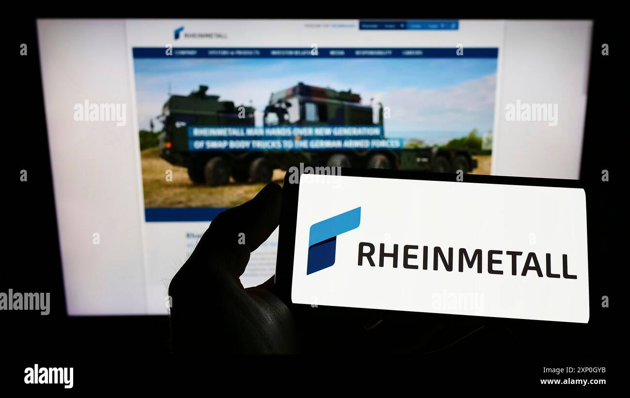 Personne tenant un smartphone avec le logo de la société de défense allemande Rheinmetall AG sur l'écran en face du site Web. Concentrez-vous sur l'affichage du téléphone Banque D'Images