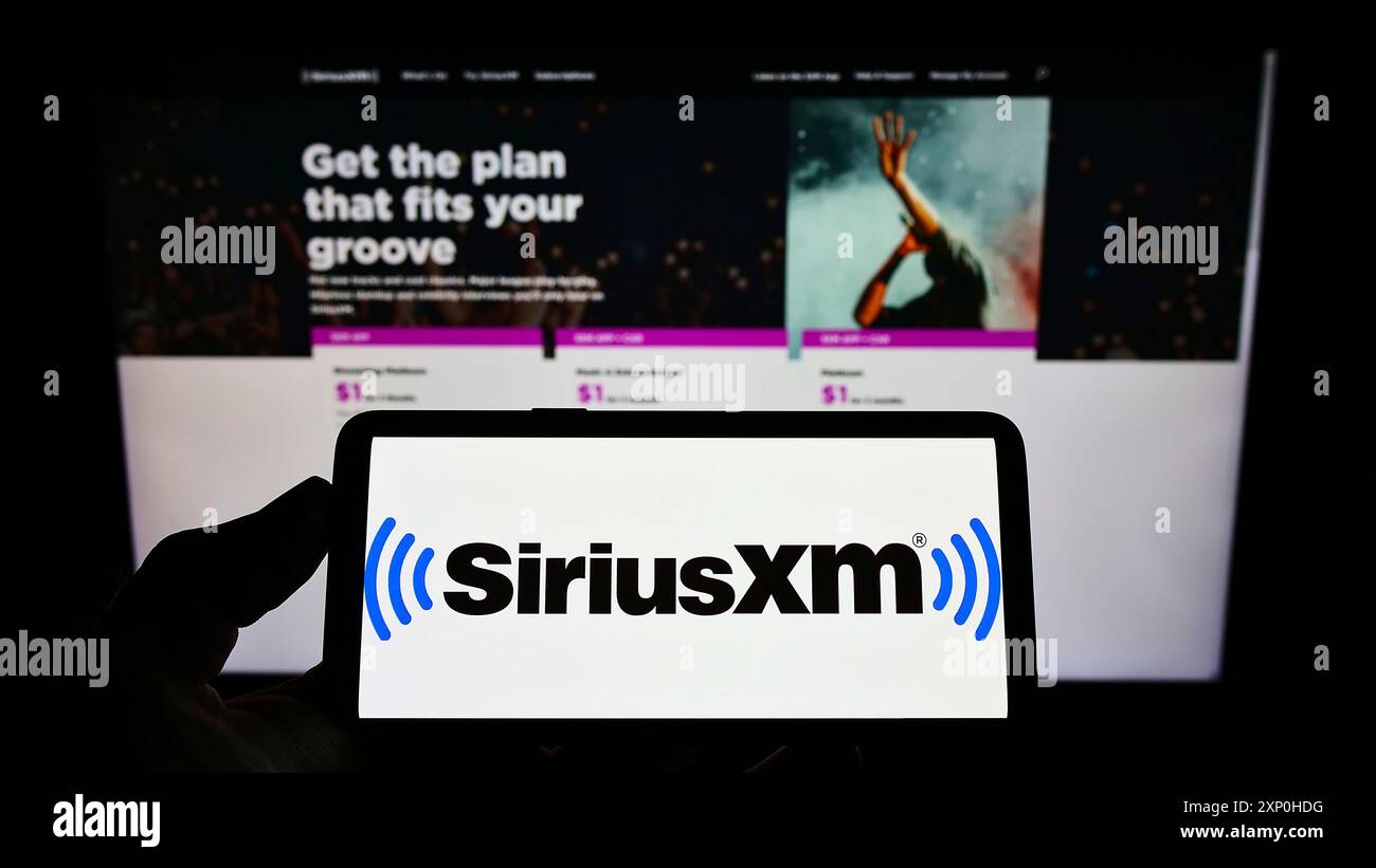 Stuttgart, Allemagne, 02-13-2022 : personne tenant un smartphone avec le logo de la société de radiodiffusion américaine Sirius XM Holdings Inc sur l'écran devant le site Web. Banque D'Images