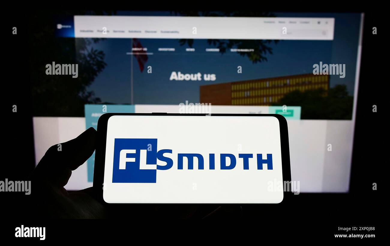Stuttgart, Allemagne, 01-30-2022, personne tenant un téléphone portable avec le logo de l'ingénierie danoise FLSmidth Co. COMME sur l'écran devant la page Web de l'entreprise. Banque D'Images