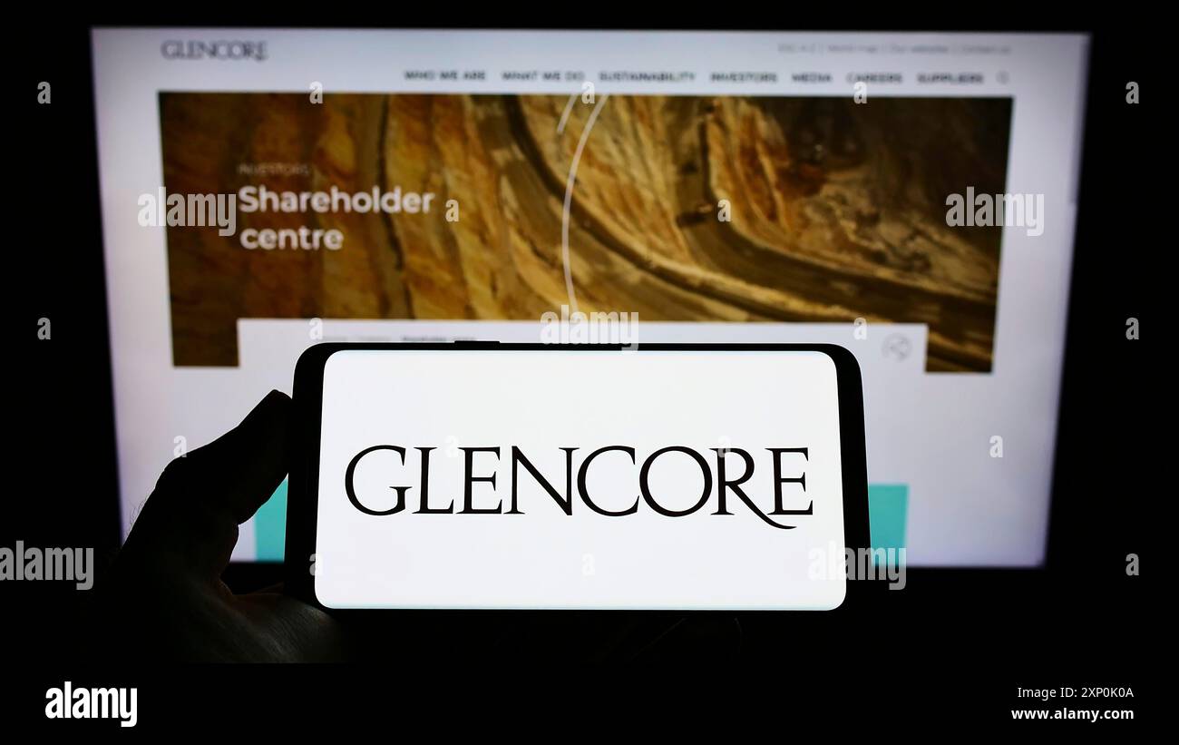 Stuttgart, Allemagne, 01-28-2022, personne tenant le téléphone portable avec le logo de la société de négoce de marchandises Glencore plc sur l'écran devant le web d'affaires Banque D'Images