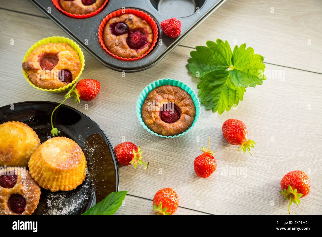 Muffins au lait caillé sucré garnis de fraises, dans une assiette sur une table en bois. Banque D'Images