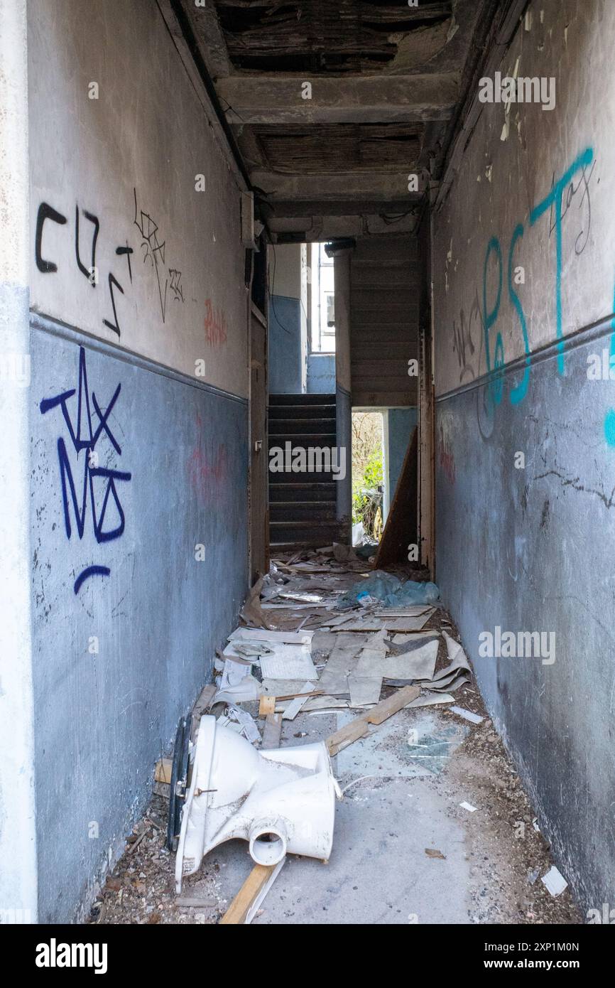 Couloir et cage d'escalier abandonnés et abandonnés dans un immeuble à Clune Park, Port Glasgow. Graffiti sur le mur et toilettes cassées. Banque D'Images