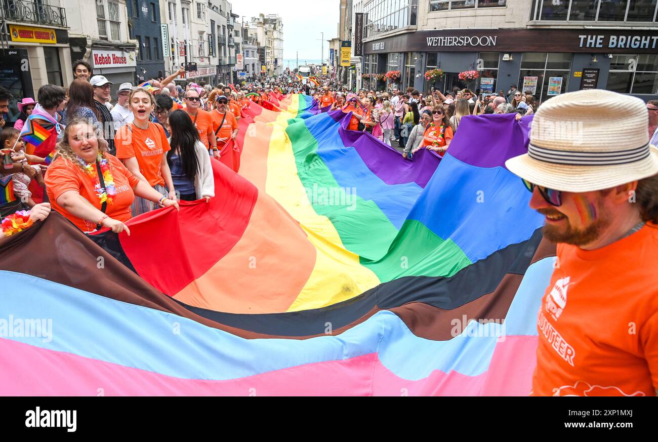 Brighton Royaume-Uni 3 août 2024 - Un drapeau arc-en-ciel géant est porté par les rues alors que des milliers de personnes prennent part à cette parade Brighton & Hove Pride Parade sur une journée blustery dans le Sud. Des milliers de personnes devraient participer au plus grand événement de la fierté du Royaume-Uni avec pour thème cette année JOY C Celebrating Life , Spirit and Resilience : Credit Simon Dack / Alamy Live News Banque D'Images