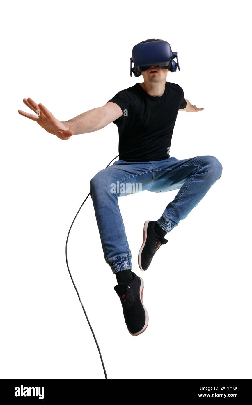 Jeune homme volant sur fond blanc comme super-héros tout en regardant dans des lunettes VR. Concept de gadgets et de technologies modernes. Guy utilisant des lunettes 3D. Banque D'Images