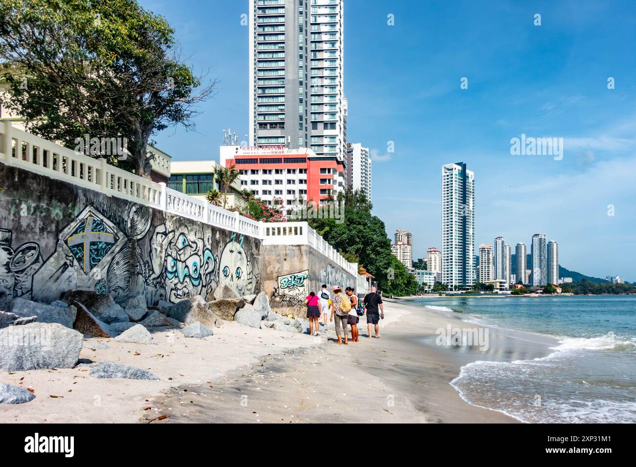 Une famille marchant le long de la plage de Tanjing Tokong à Penang, Malaisie avec de grands gratte-ciel modernes, une partie d'un paysage urbain en arrière-plan. Banque D'Images