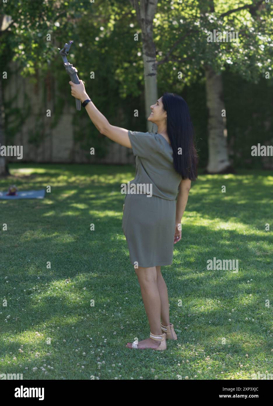 Une femme se prend en photo avec un appareil photo. Elle porte une robe verte et des sandales Banque D'Images