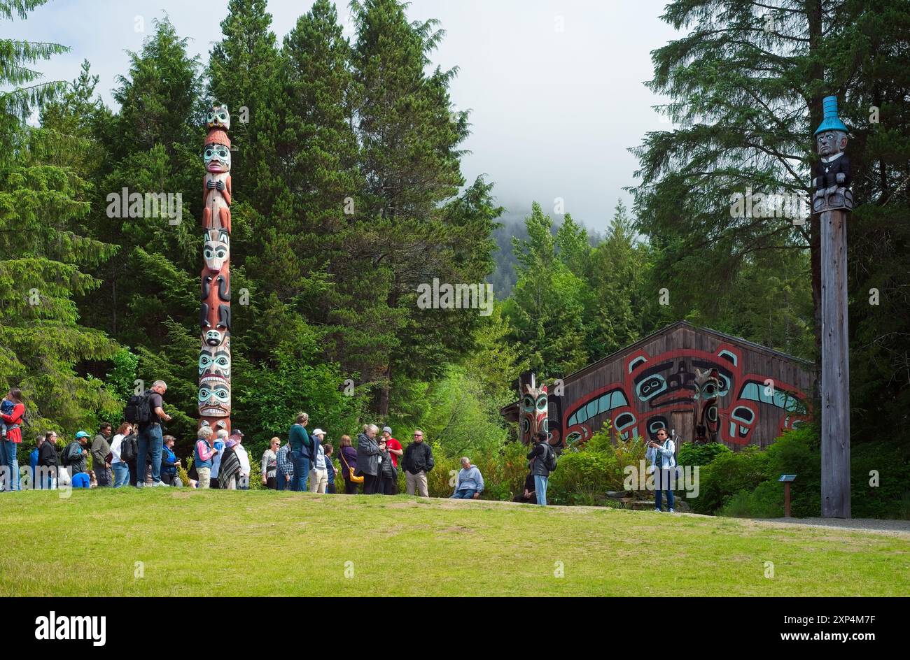 Un groupe de touristes se réunit près de deux des 25 poteaux du parc Saxman Totem près de Ketchikan. Banque D'Images