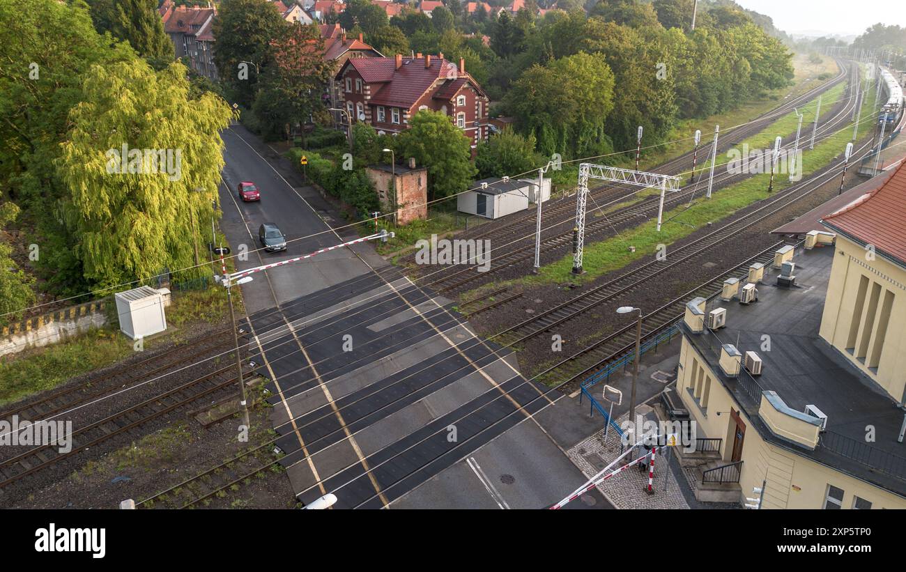 Voies ferrées traversant près d'un quartier résidentiel avec des voitures et des piétons dans Early Morning Light Banque D'Images