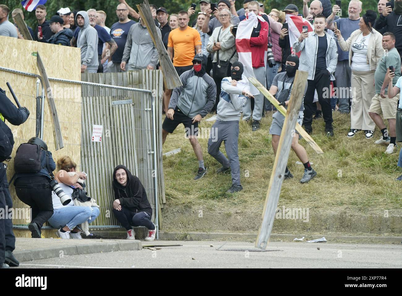 Une femme et un homme se mettent à couvert alors que des objets sont lancés lors d'une manifestation anti-immigration devant le Holiday Inn Express à Rotherham, dans le South Yorkshire. Date de la photo : dimanche 4 août 2024. Banque D'Images