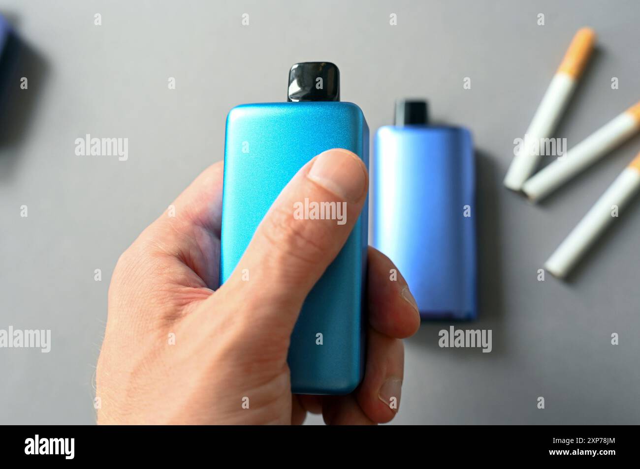 Personne tenant la cigarette électronique bleue au-dessus de la table avec des cigarettes analogiques, image conceptuelle sur la santé et la dépendance Banque D'Images