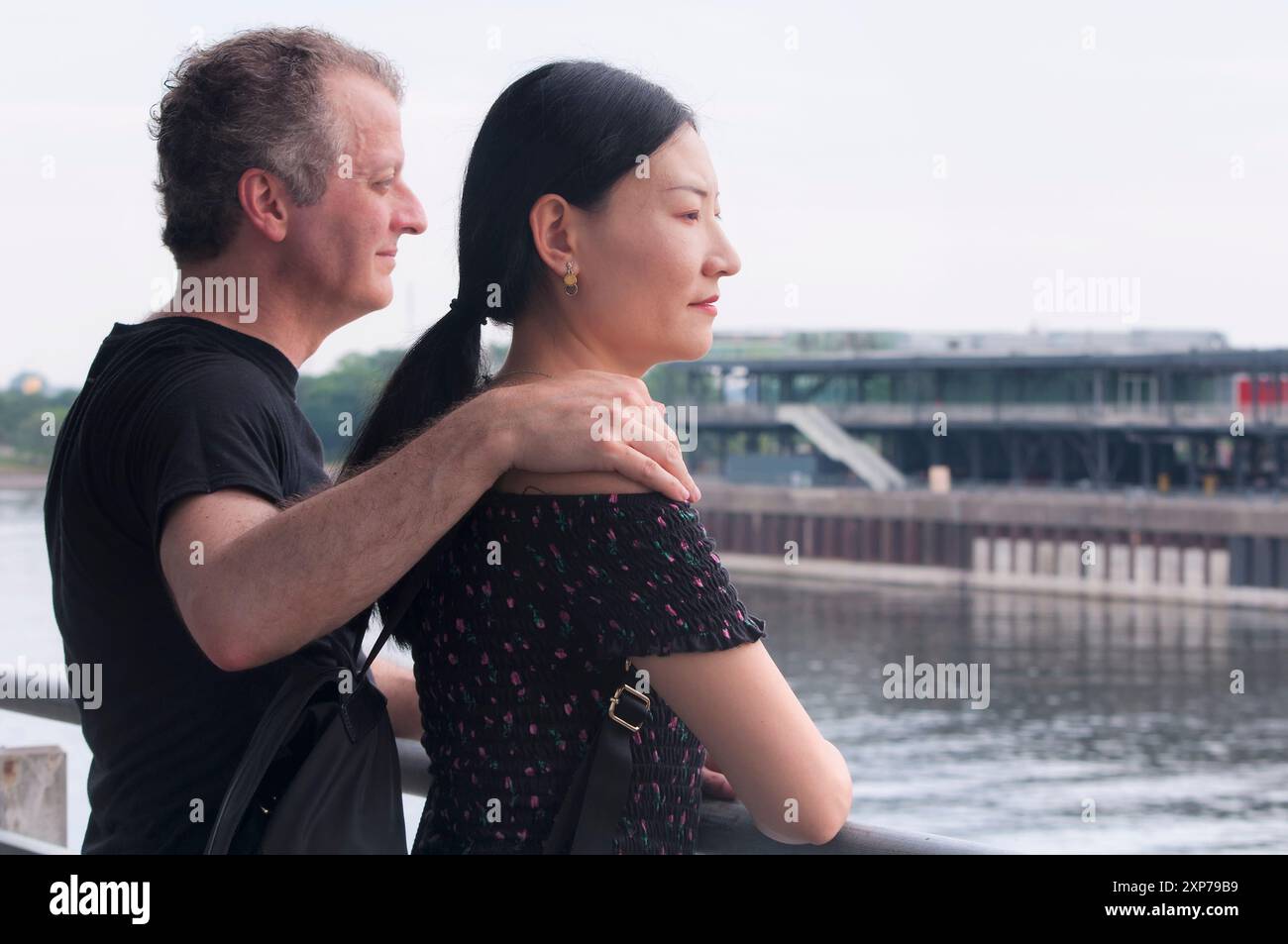 un couple bi-racial regardant au loin sur un balcon dans le vieux port de montréal canada un jour couvert. Banque D'Images