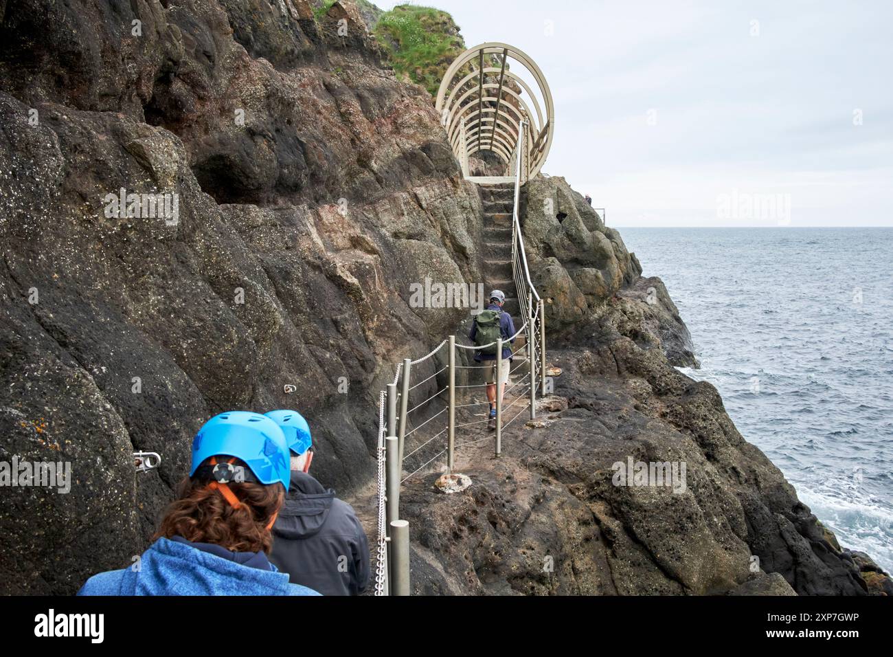 guide guide guide les touristes le long de la promenade côtière des gobbins vers le pont tubulaire comté d'antrim, irlande du nord, royaume-uni Banque D'Images