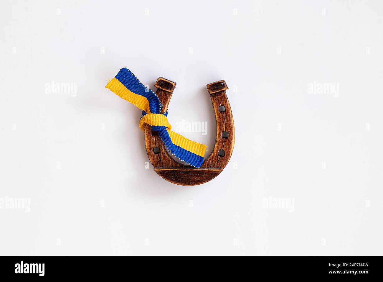 Un fer à cheval en bois attaché avec un ruban de drapeau ukrainien est accroché à un réfrigérateur à la maison en Ukraine, symbole ukrainien de chance et de fortune Banque D'Images