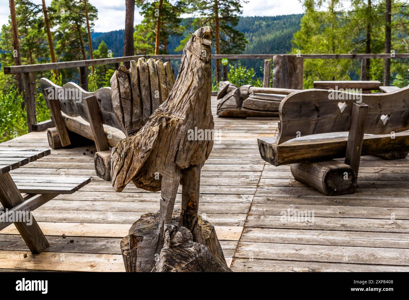 Une sculpture en bois sculpté, peut-être une représentation stylisée d'un tétras lyre (Auerhahn), se dresse parmi des bancs en bois sculptés à la main sur la plateforme des myrtilles (Heidelbeerplattform) près d'Enzklösterle. Bad Wildbad, Bade-Wurtemberg, Allemagne. Banque D'Images
