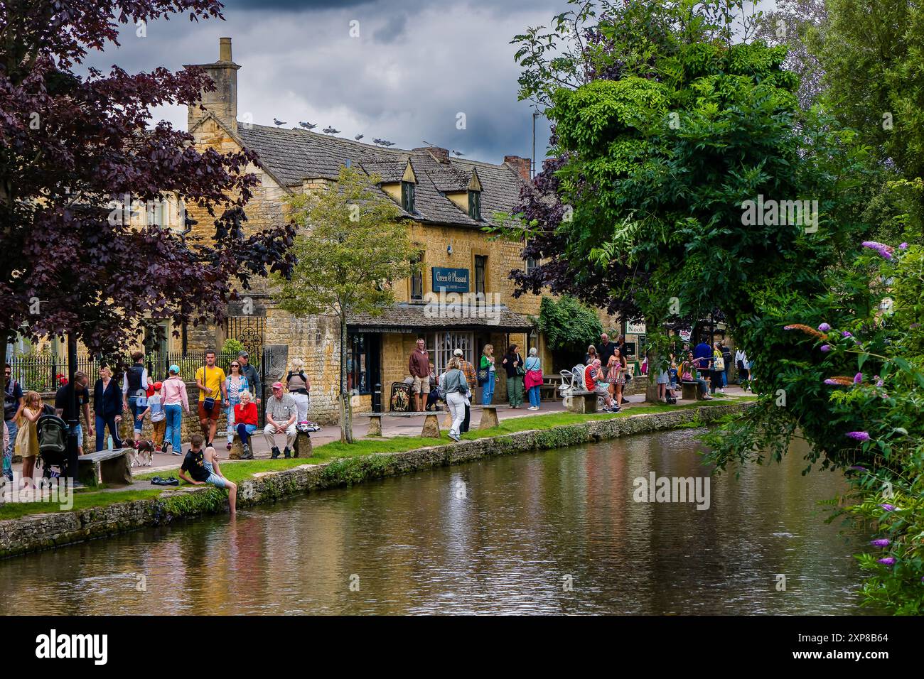 Touristes dans l'ancien village traditionnel des Cotswolds de Bourton-on-the-Water en été Banque D'Images