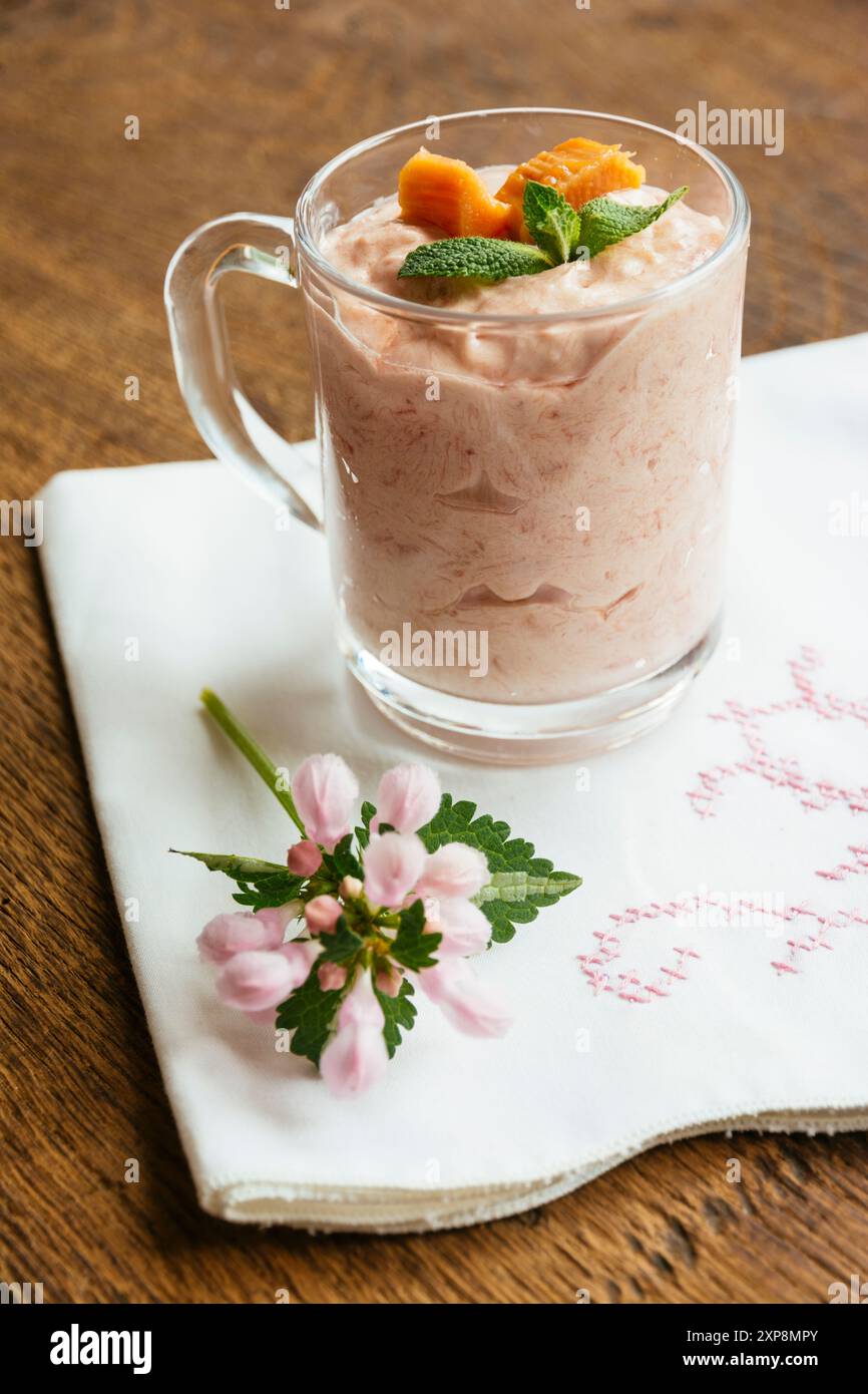 Fou de rhubarbe avec compote de rhubarbe (rhubarbe sucre vanille), crème de coco, sucre en poudre et feuilles de menthe comme garniture. Banque D'Images