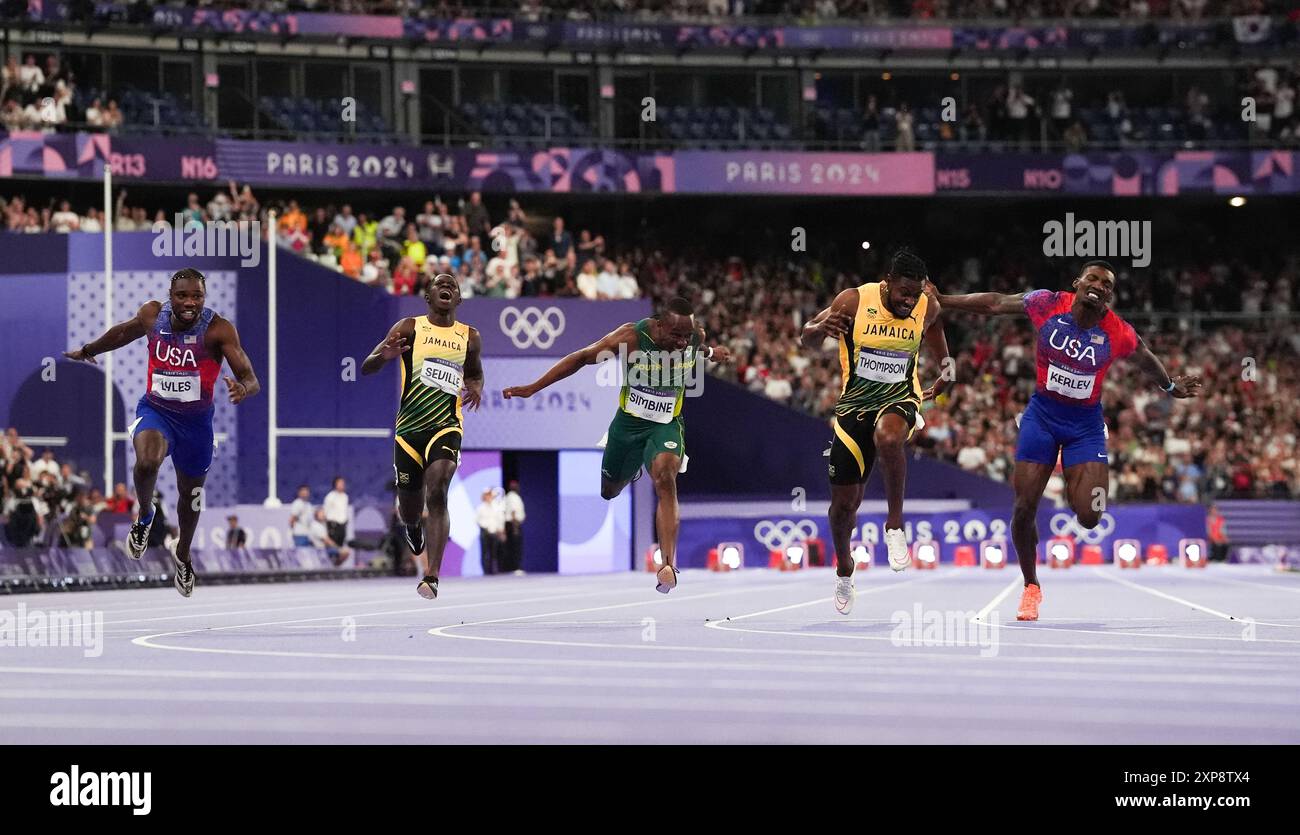 L'américain Noah Lyles (à gauche) et la jamaïcaine Kishane Thompson (à droite) franchissent la ligne d'arrivée lors de la finale du 100 m masculin au stade de France, la neuvième journée des Jeux Olympiques de Paris 2024 en France. Le champion du monde de sprint Noah Lyles a pris d’assaut l’or olympique avec une marge de seulement cinq millièmes de seconde au stade de France. L’américain a franchi la ligne en 9,79 secondes, le même temps que celui qui apparaissait sur le tableau de bord pour la jamaïcaine Kishane Thompson. Les deux hommes ont attendu avec un souffle appâté lorsque le résultat a été confirmé, avec le coéquipier américain de Lyles complétant le podium en 9,81. Date de la photo : dimanche 4 août Banque D'Images