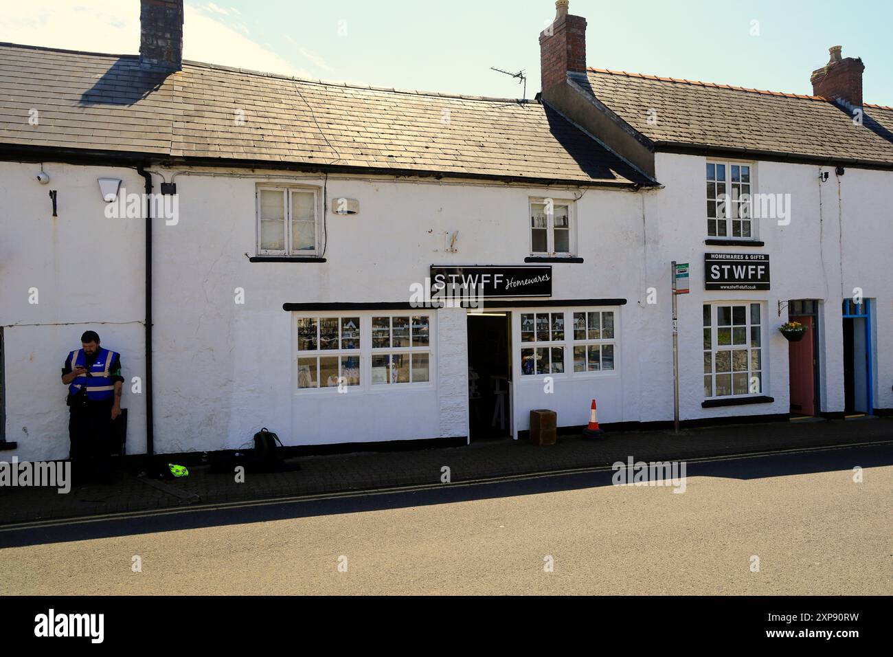 Garde de sécurité en service devant le magasin de tournage, Llantwit Major pendant le tournage de la série télévisée de la BBC Death Valley. 26 juillet 2024. Été Banque D'Images