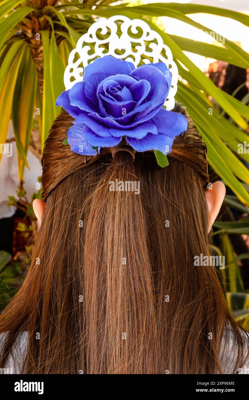 Fille avec une fleur dans ses longs cheveux brunetta pendant la célébration de la Fiesta. Banque D'Images