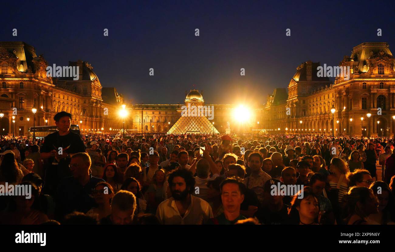 Paris, France - 2 août 2024 : la foule s'est rassemblée entre le Musée du Louvre et le jardin des Tuileries au coucher du soleil pour assister au vol de la flamme olympique Ba Banque D'Images