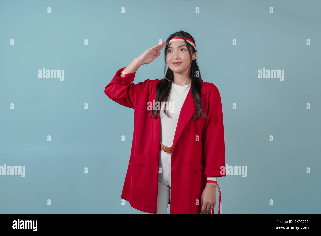 Femme indonésienne souriante portant une veste rouge et un bandeau drapeau faisant un geste de salut. Concept du jour de l'indépendance indonésienne. Banque D'Images