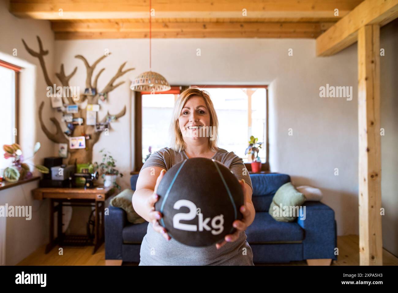 Femme en surpoids exerçant à la maison, en utilisant le medecine ball pondéré. Entraînez-vous dans le salon. Banque D'Images