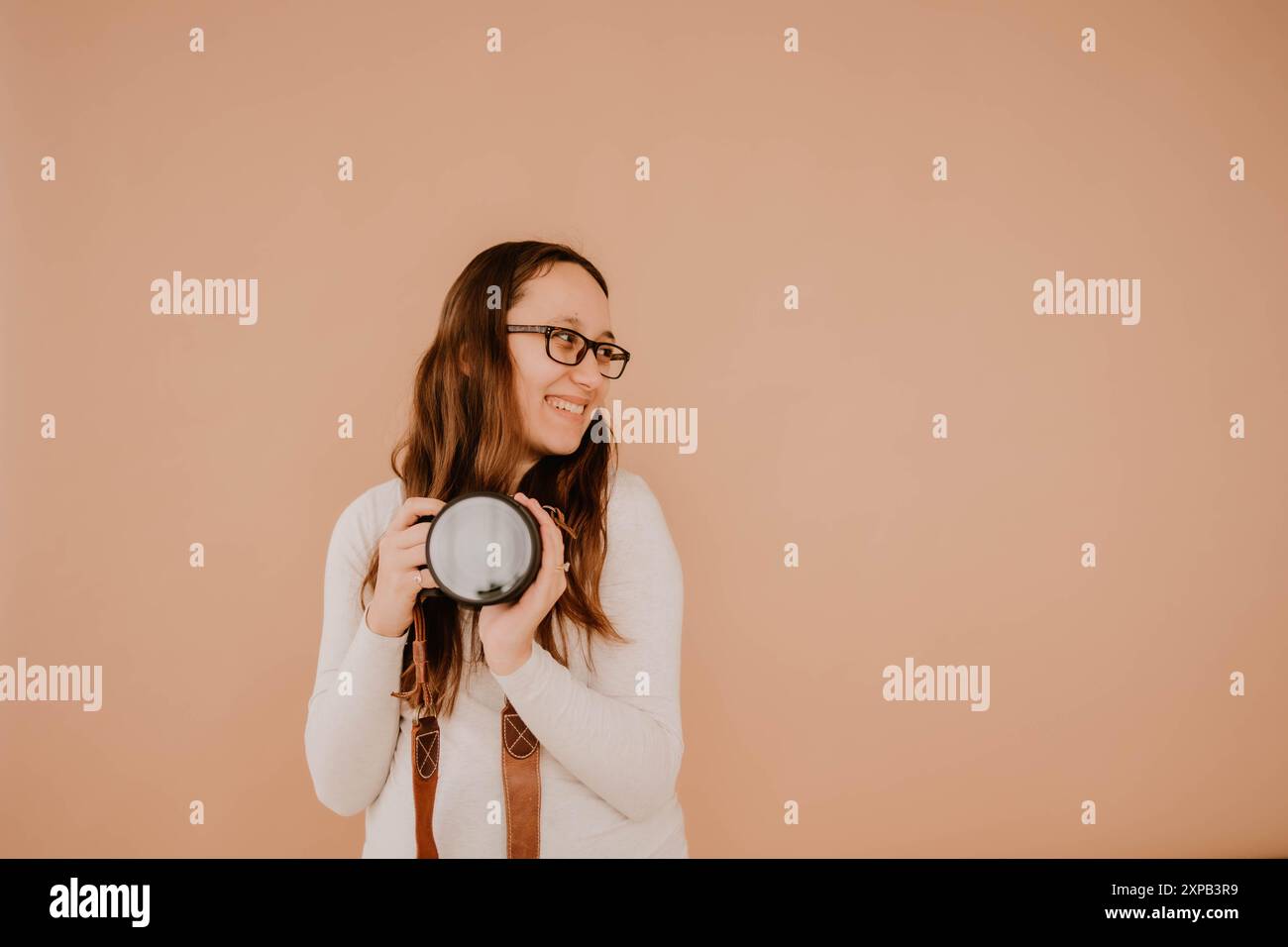 Souriant jeune photographe hispanique tenant un appareil photo Banque D'Images