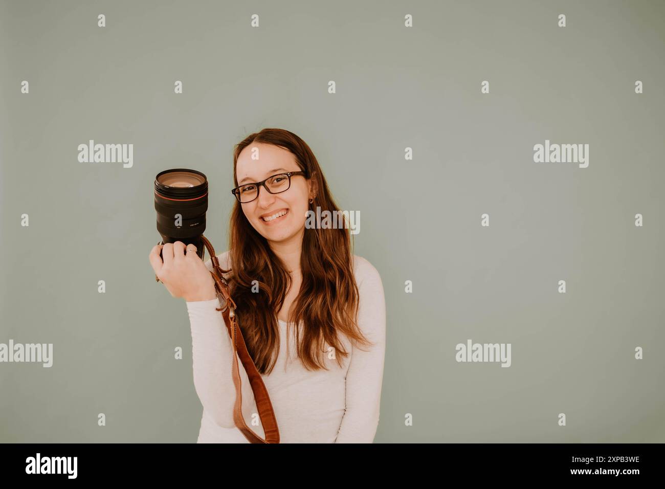 Photographe hispanique souriante tenant un appareil photo Banque D'Images