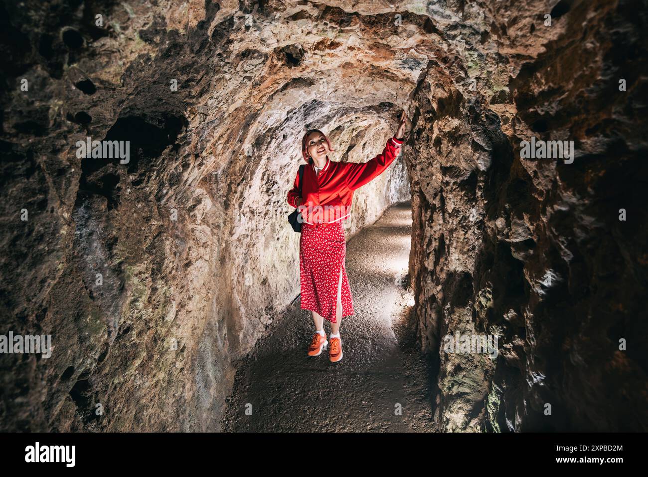 Une femme explore une grotte karstique unique, debout au milieu de stalagmites et stalactites illuminées, immergée dans la beauté géologique antique souterraine. Banque D'Images