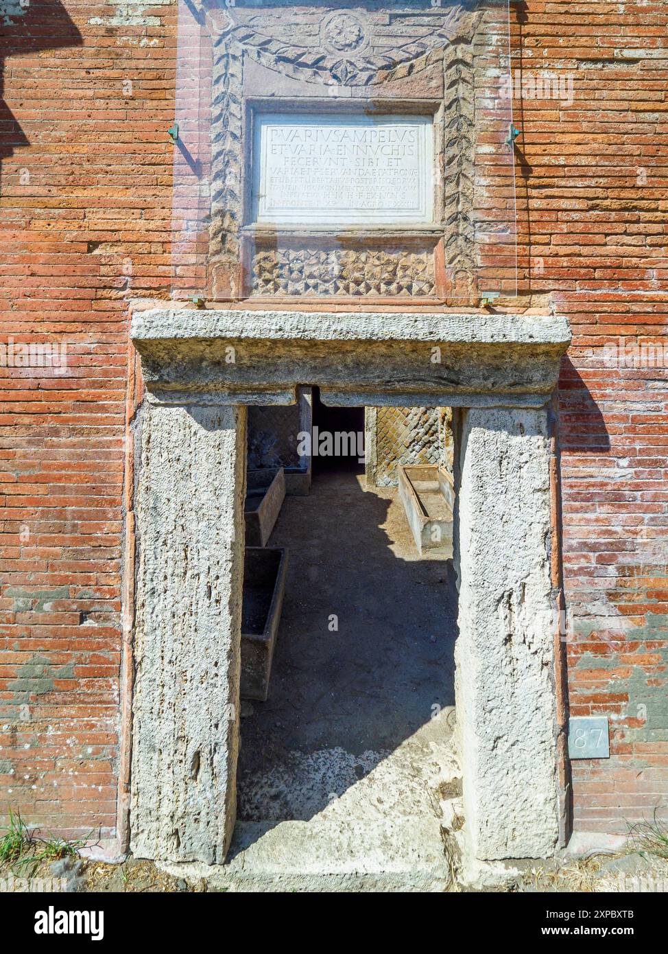 Bâtiment funéraire d'un ou deux étages carrés, souvent entouré d'un enclos ; plafonds voûtés en tonneau ou toits plats ; façades composées de briques ornées de pignons triangulaires, de socles, de lesènes, de colonnes et de chapiteaux ; petites fenêtres et portes encadrées de seuils en travertin, de montants et d'épistyles. La nécropole s'est développée sur les côtés de la via Flavia entre la fin des Ier et IVe siècles après JC - nécropole de Portus dans l'Isola Sacra, Fiumicino, Rome, Italie Banque D'Images