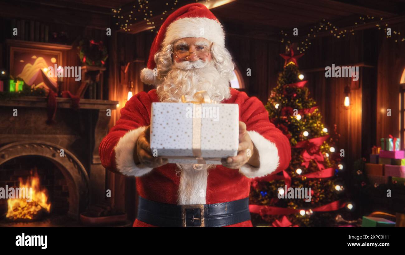 Portrait d'un Père Noël heureux offrant un cadeau blanc magnifiquement enveloppé aux enfants. Vieil homme regardant Camera, souriant tout en donnant le présent. Concept des fêtes de Noël et du nouvel an Banque D'Images