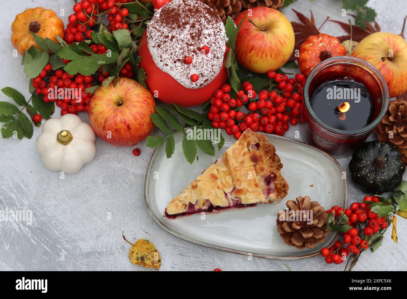 Nature morte d'automne avec une tasse de café chaud, tarte aux myrtilles, bougie, citrouilles et baies de rowan. Tarte sucrée de saison maison sur une table. Banque D'Images