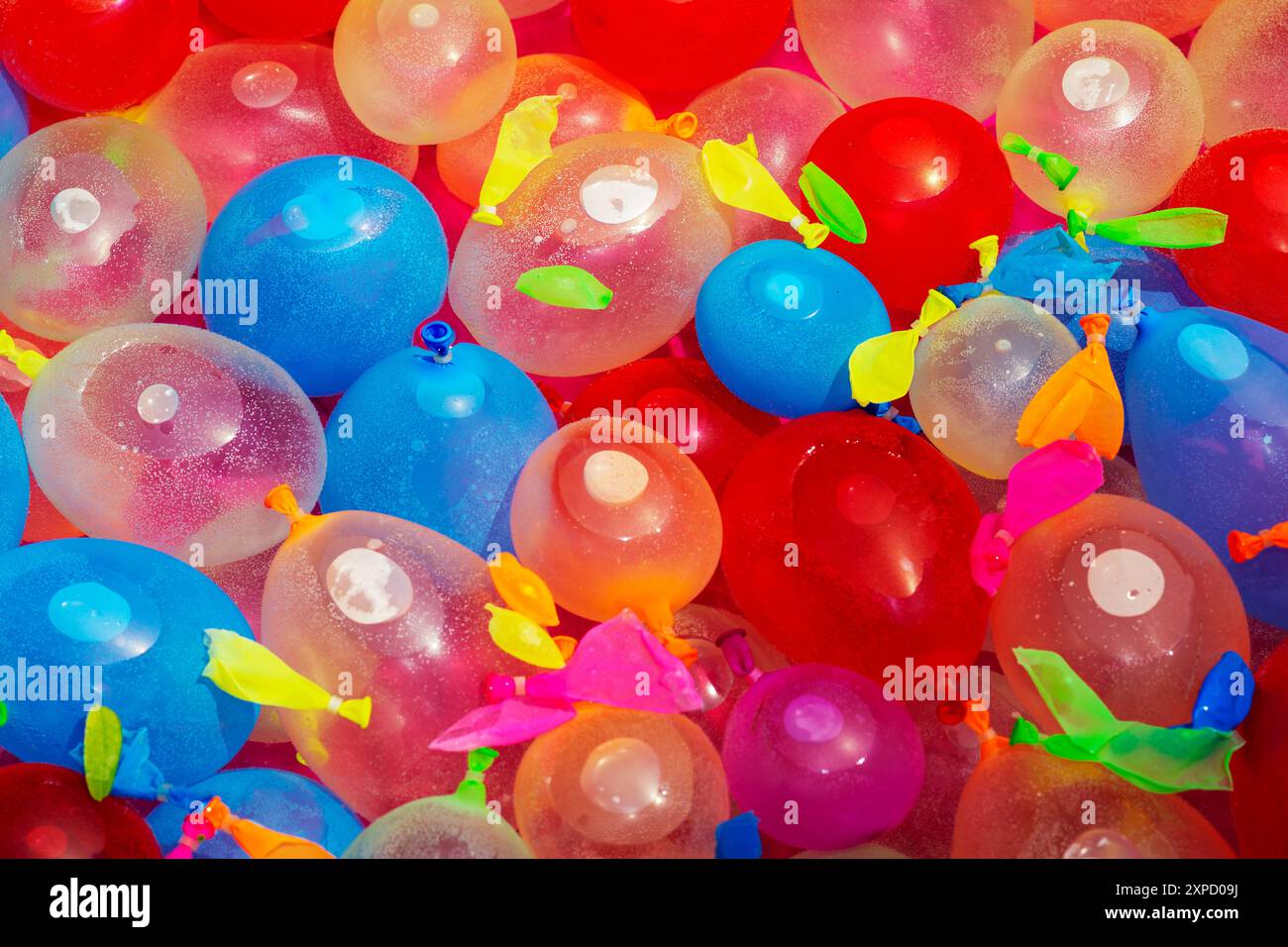 Gros plan d'une piscine rose extérieure pastique remplie de ballons d'eau multicolores pour une fête d'anniversaire. Banque D'Images