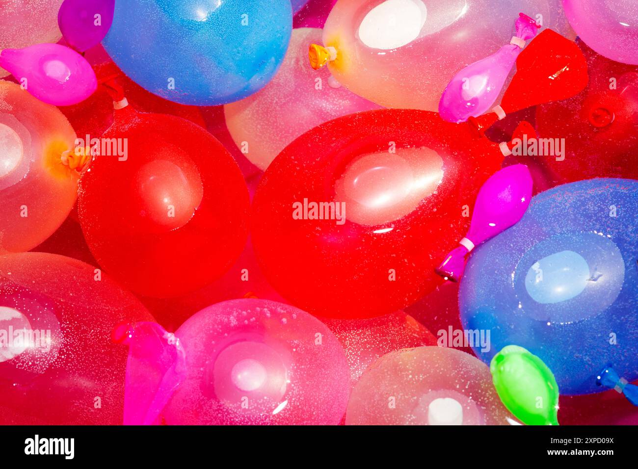 Gros plan d'une piscine rose extérieure pastique remplie de ballons d'eau multicolores pour une fête d'anniversaire. Banque D'Images