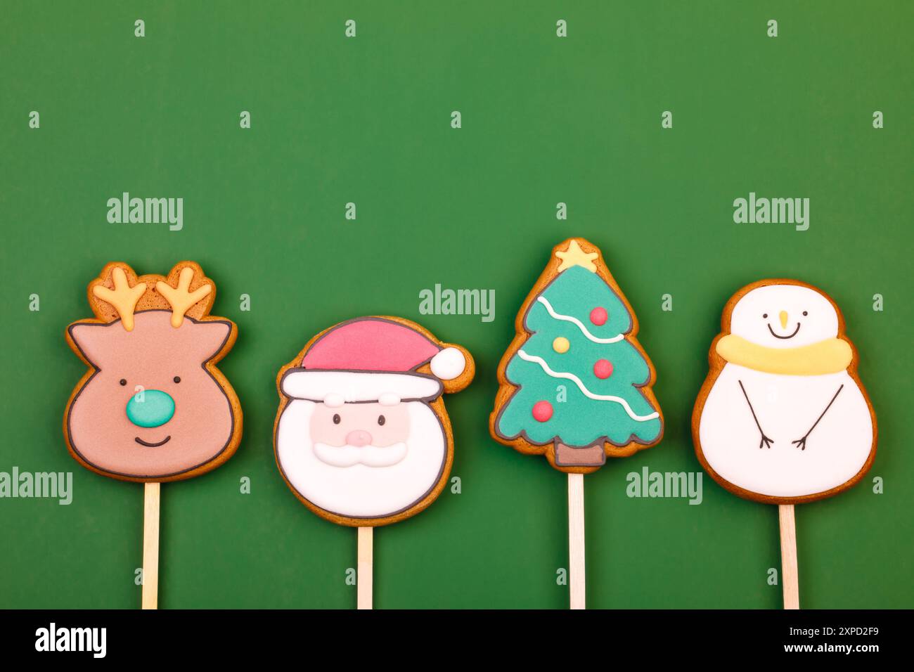 Biscuits glacés sur le thème de Noël en forme de renne, Père Noël, arbre de Noël et bonhomme de neige sur fond vert Banque D'Images