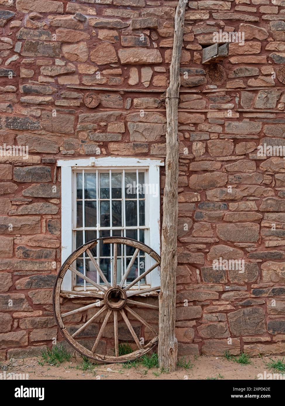 Roue de wagon en bois appuyée sur le rebord de fenêtre dans le mur de pierre de Hubbell Trading Post Banque D'Images