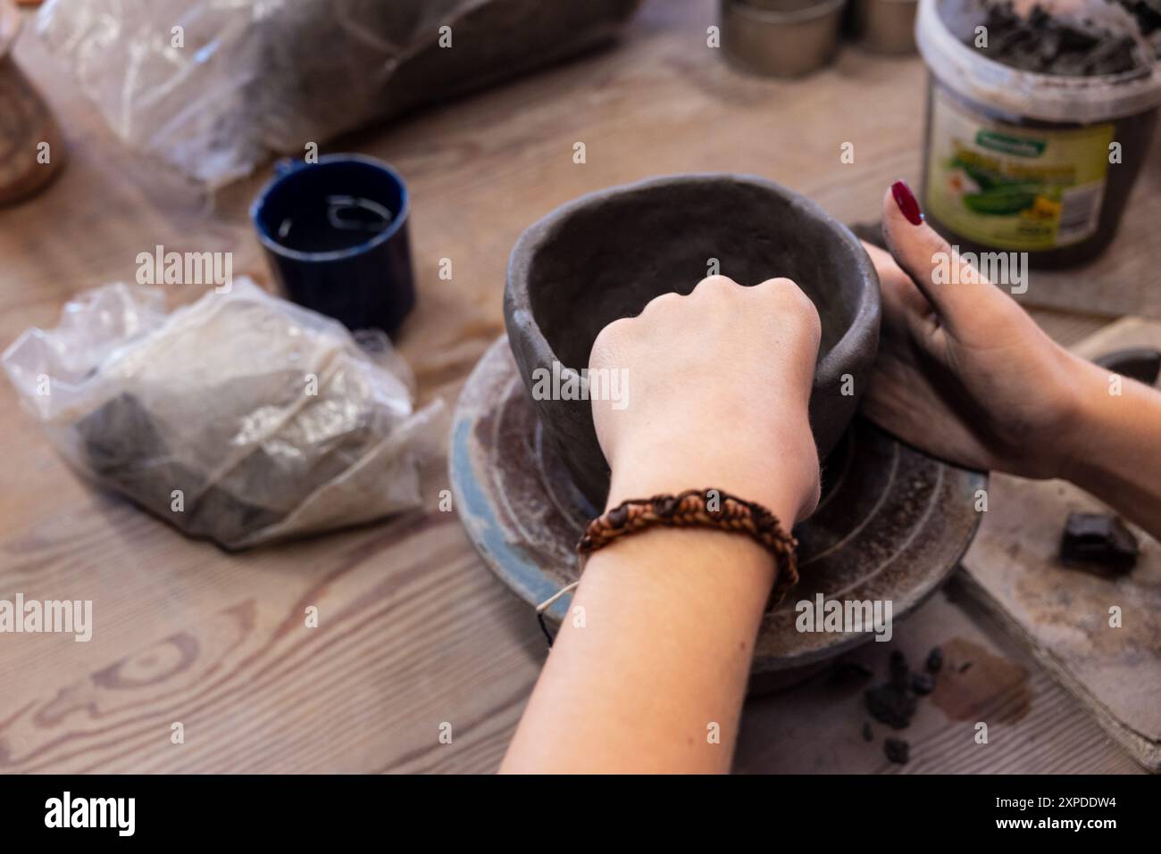 mains féminines sculptant un pot dans de l'argile pendant un cours de poterie Banque D'Images