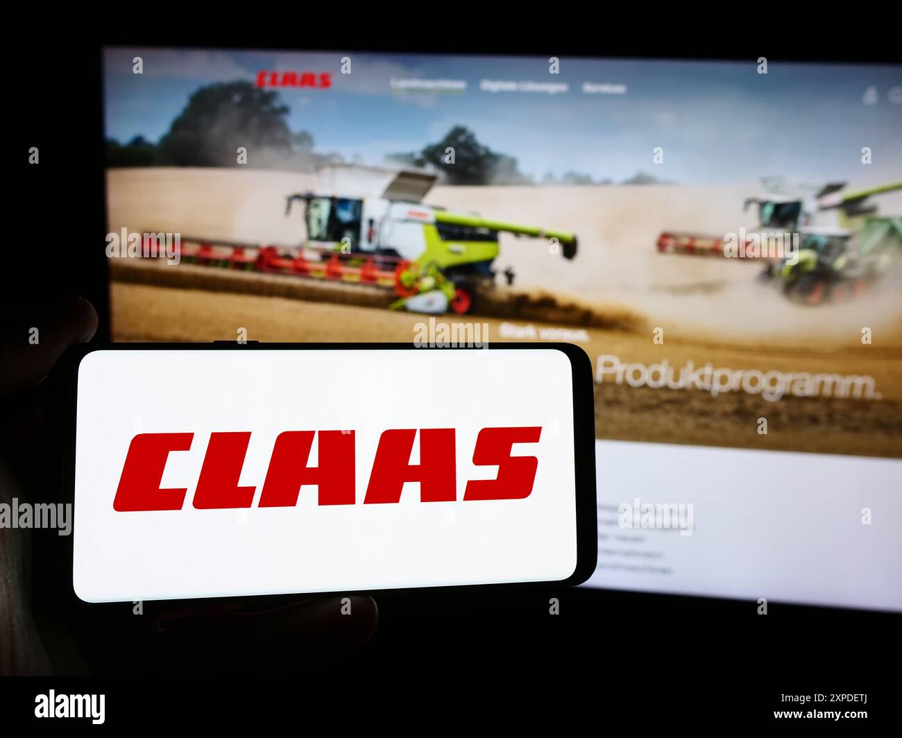 Personne tenant un smartphone avec le logo de la société allemande de machines agricoles Claas KGaA mbH en face du site Web. Concentrez-vous sur l'affichage du téléphone. Banque D'Images