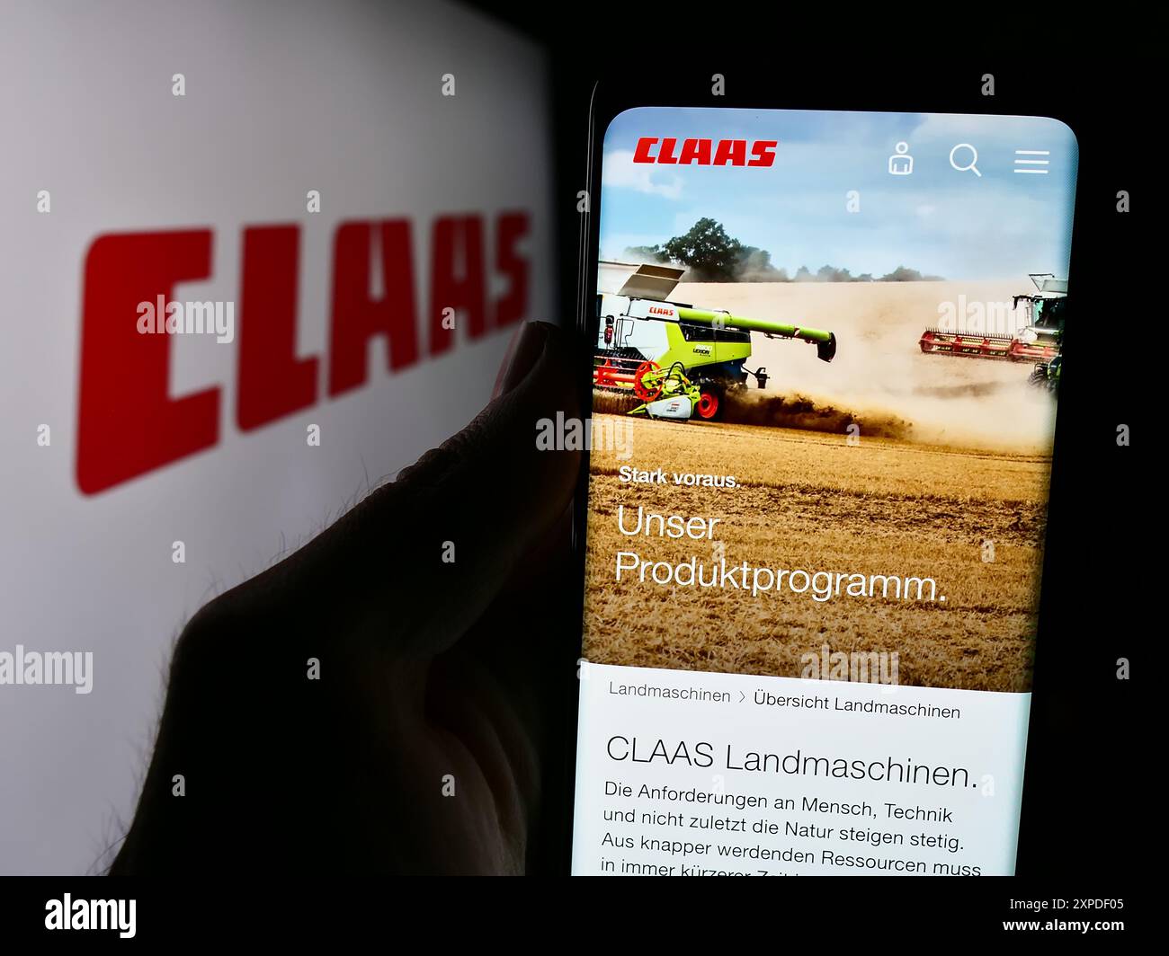 Personne tenant un téléphone portable avec la page web de la société allemande de machines agricoles Claas KGaA mbH devant le logo. Concentrez-vous sur le centre de l'écran du téléphone. Banque D'Images
