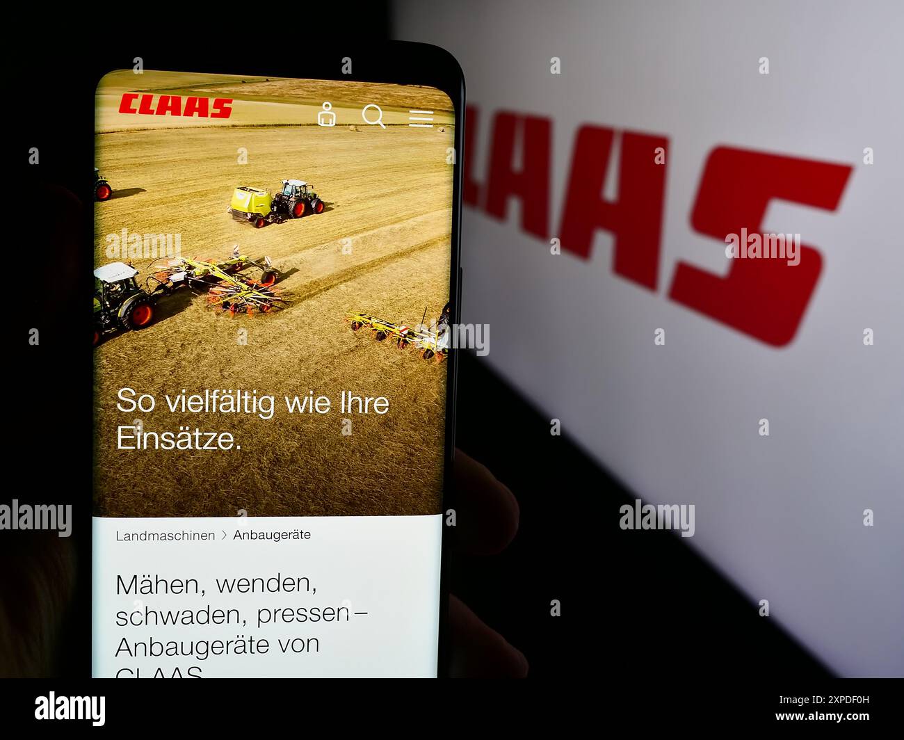 Personne tenant smartphone avec la page web de la société allemande de machines agricoles Claas KGaA mbH avec logo. Concentrez-vous sur le centre de l'écran du téléphone. Banque D'Images