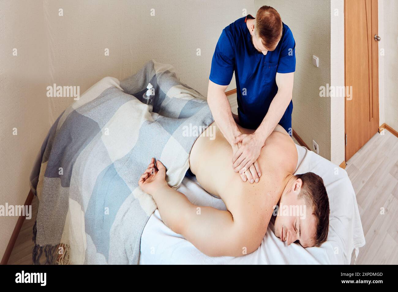 Physiothérapeute donne massage des tissus profonds à l'homme souffrant de maux de dos. Banque D'Images